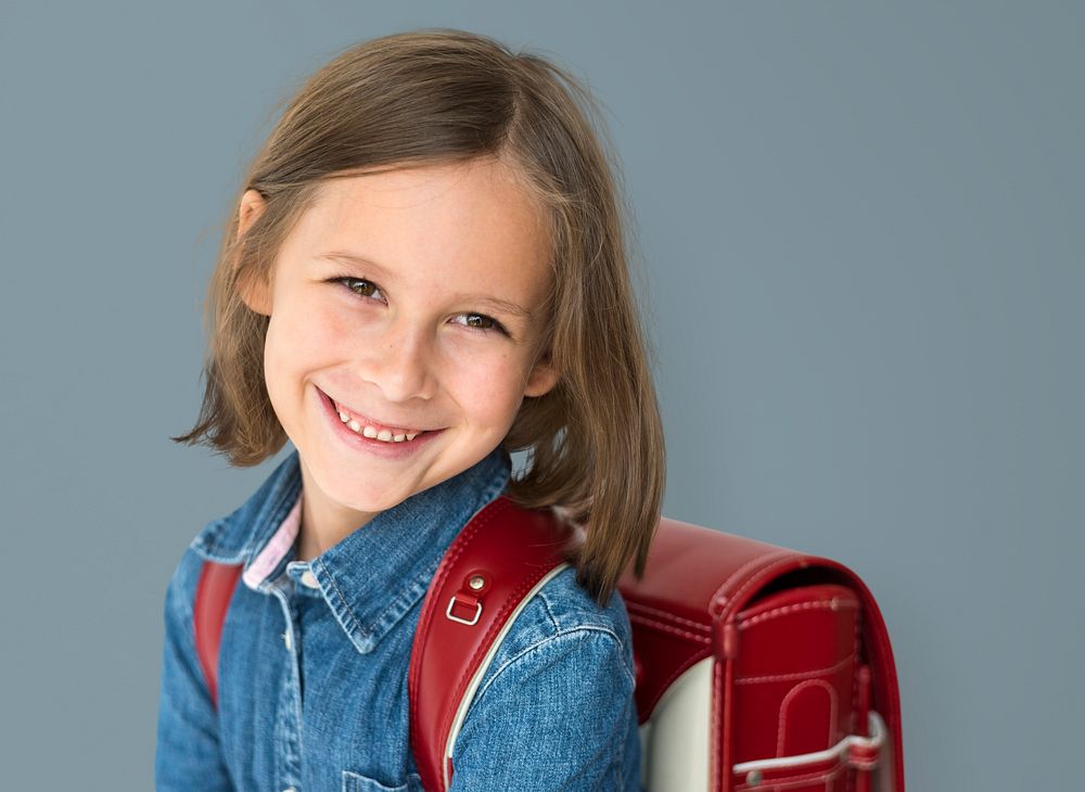 Young girl with a backpack cheerful studio portrait