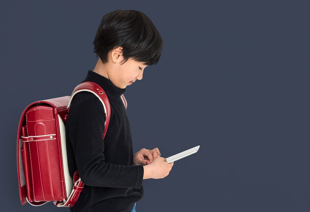 Young asian kid with a backpack using a tablet isolated portrait