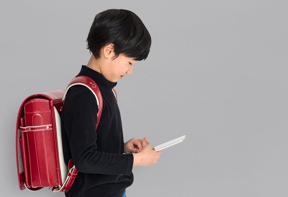 Young asian kid with a backpack using a tablet isolated portrait