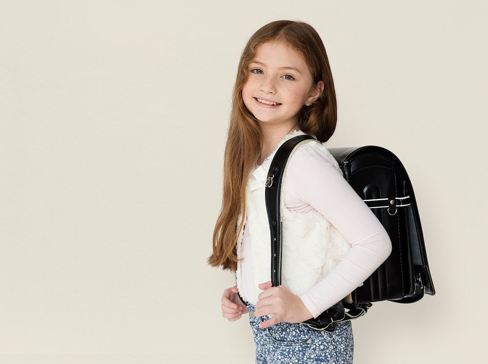 Young freckled girl carrying a backpack smiling portrait
