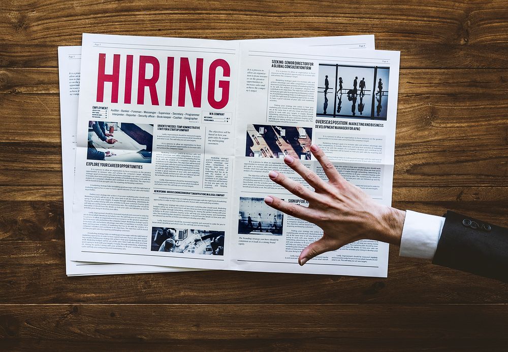Hand Reach Out for Career Hiring Job Announcement on Newspaper