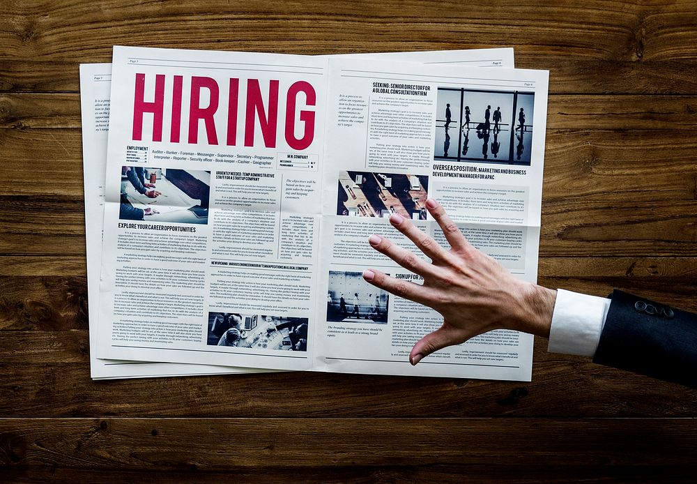 Hand Reach Out for Career Hiring Job Announcement on Newspaper