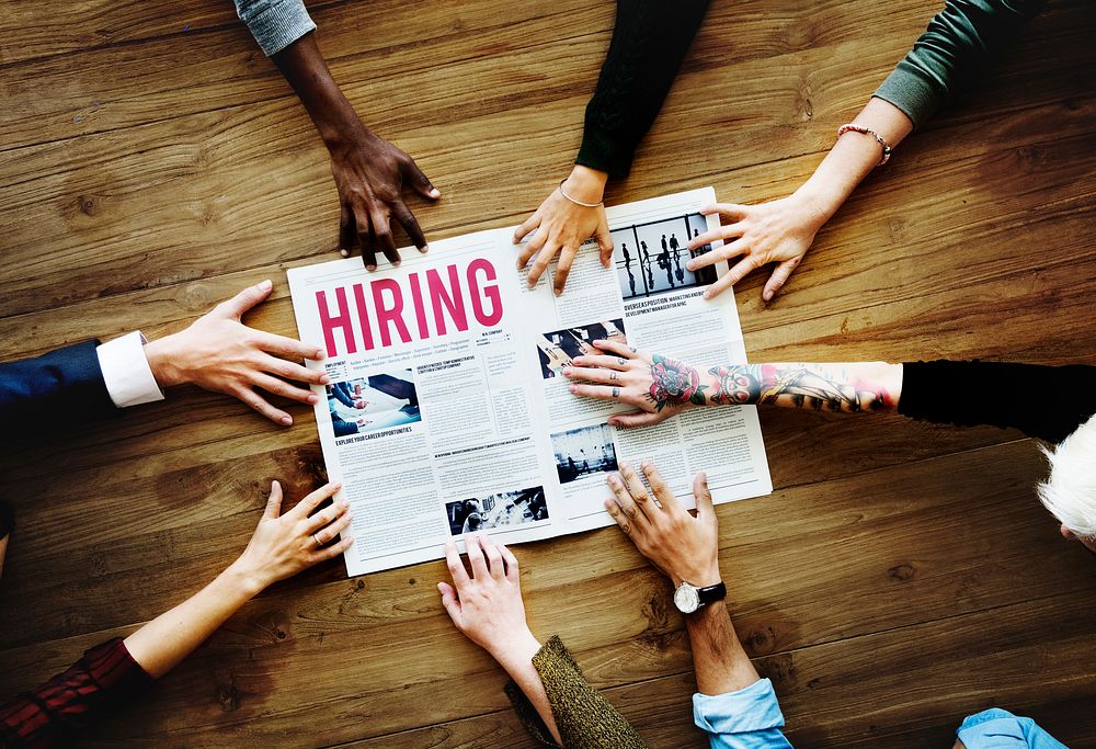 Hands Reach Out for Career Hiring Newspaper