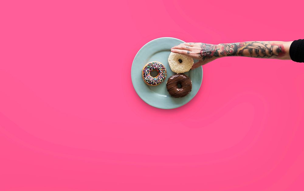 Hand with tattoo reaching for donut