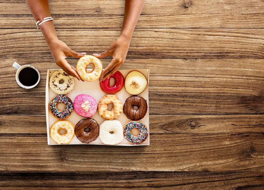 Hands holding sweeten donut dessert in aerial view