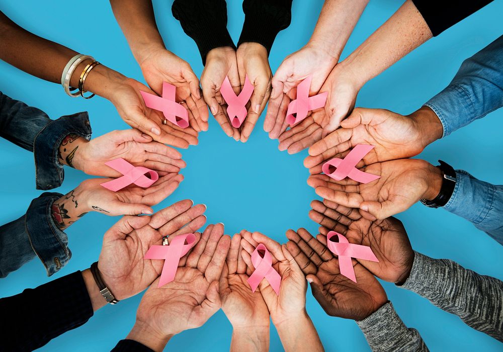 A circle of hands holding out pink ribbons
