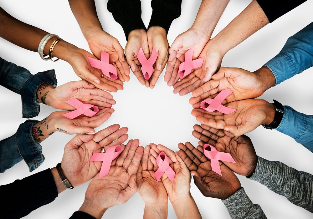 A circle of hands holding out pink ribbons