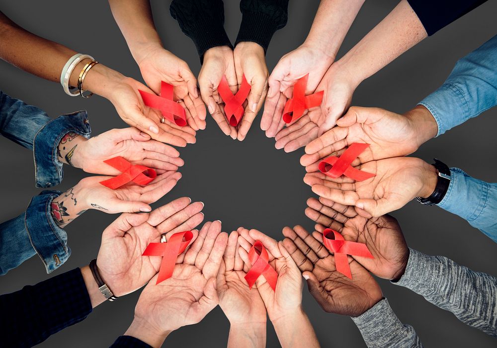 Circle of hands holding out red ribbons