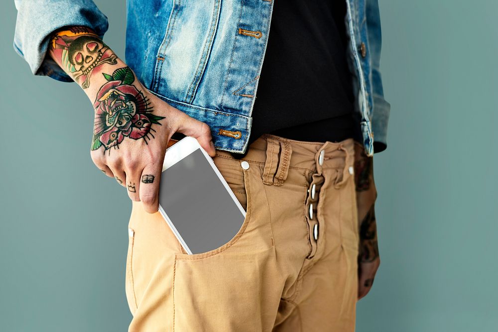 Tattooed hand with a mobile phone in the pocket