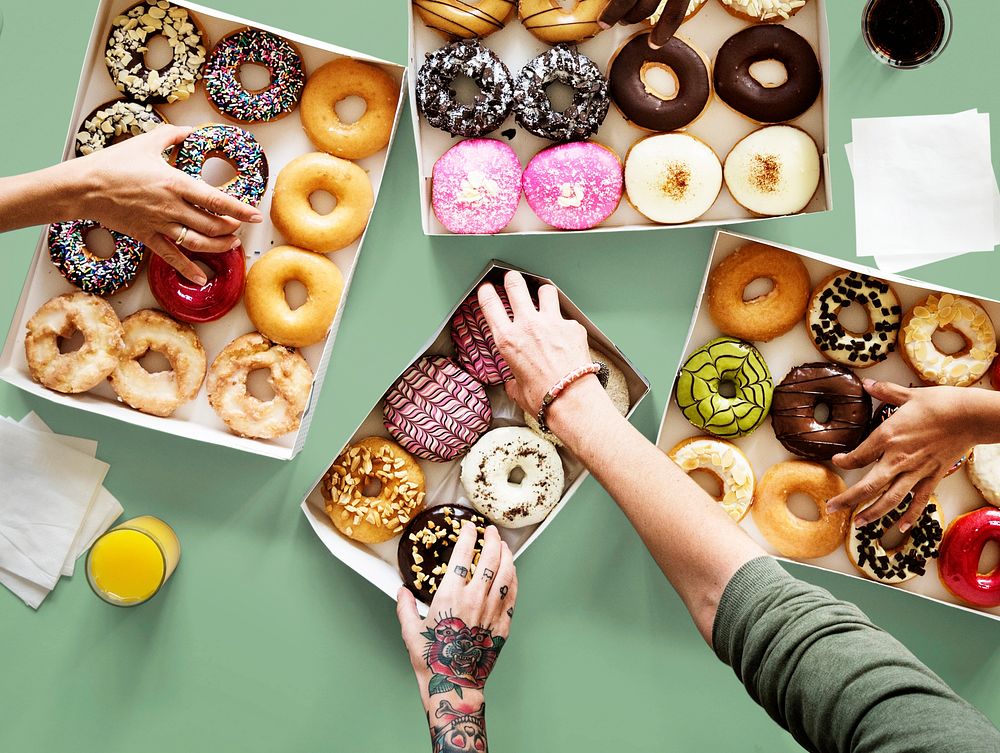 Hands selecting a variety of donut flavour