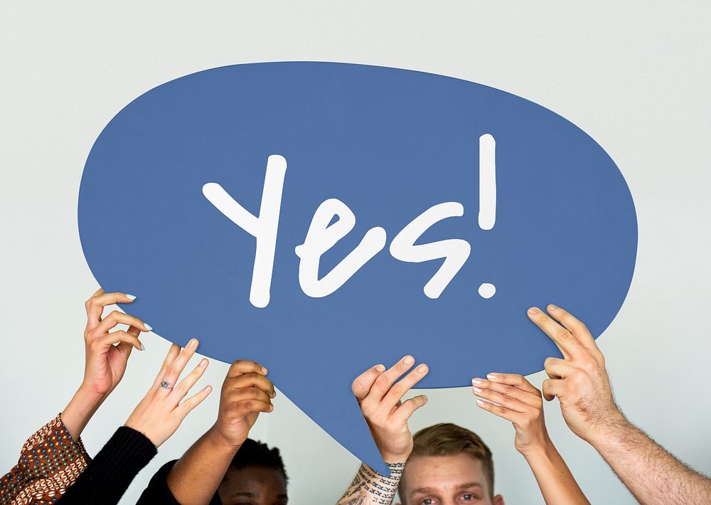 Diverse people holding a speech bubble with yes word