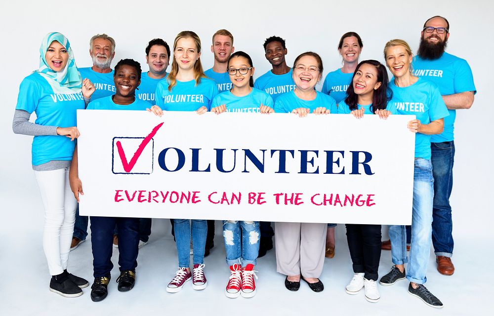 Group of volunteer people smiling and holding charity banner