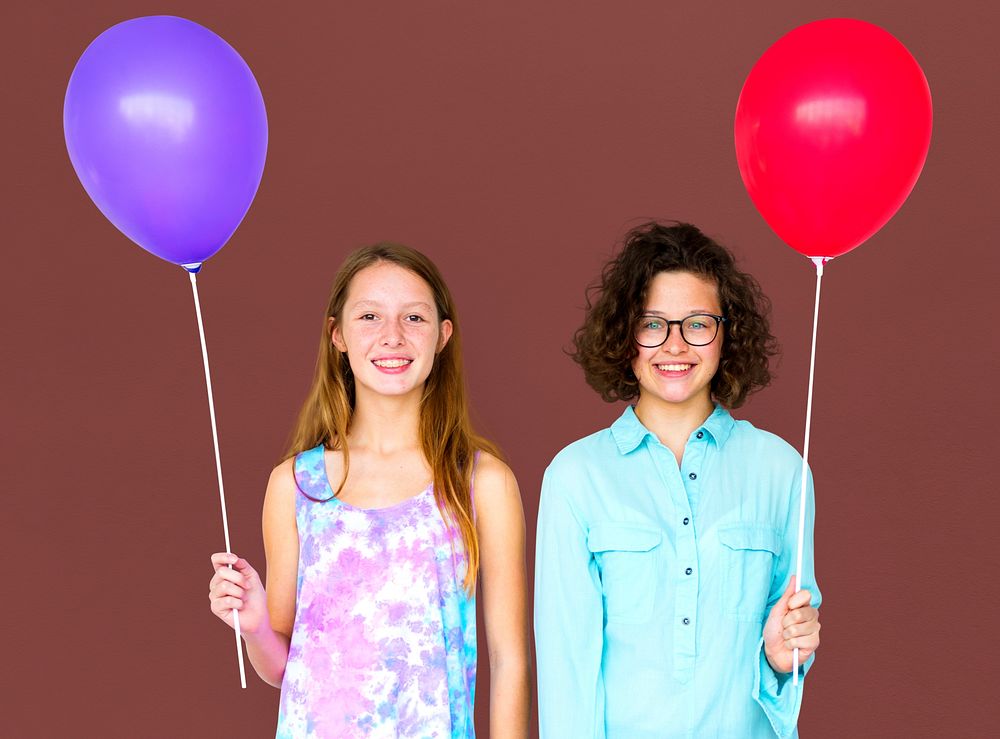 Two girl is holding a color balloon