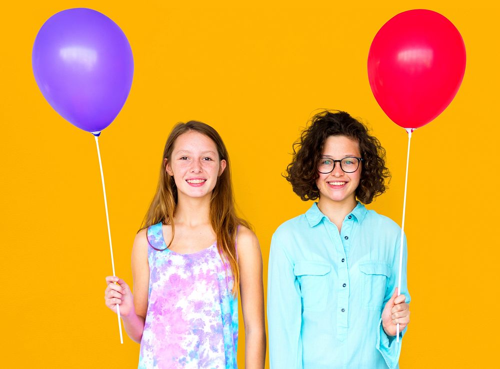 Two girl is holding a color balloon