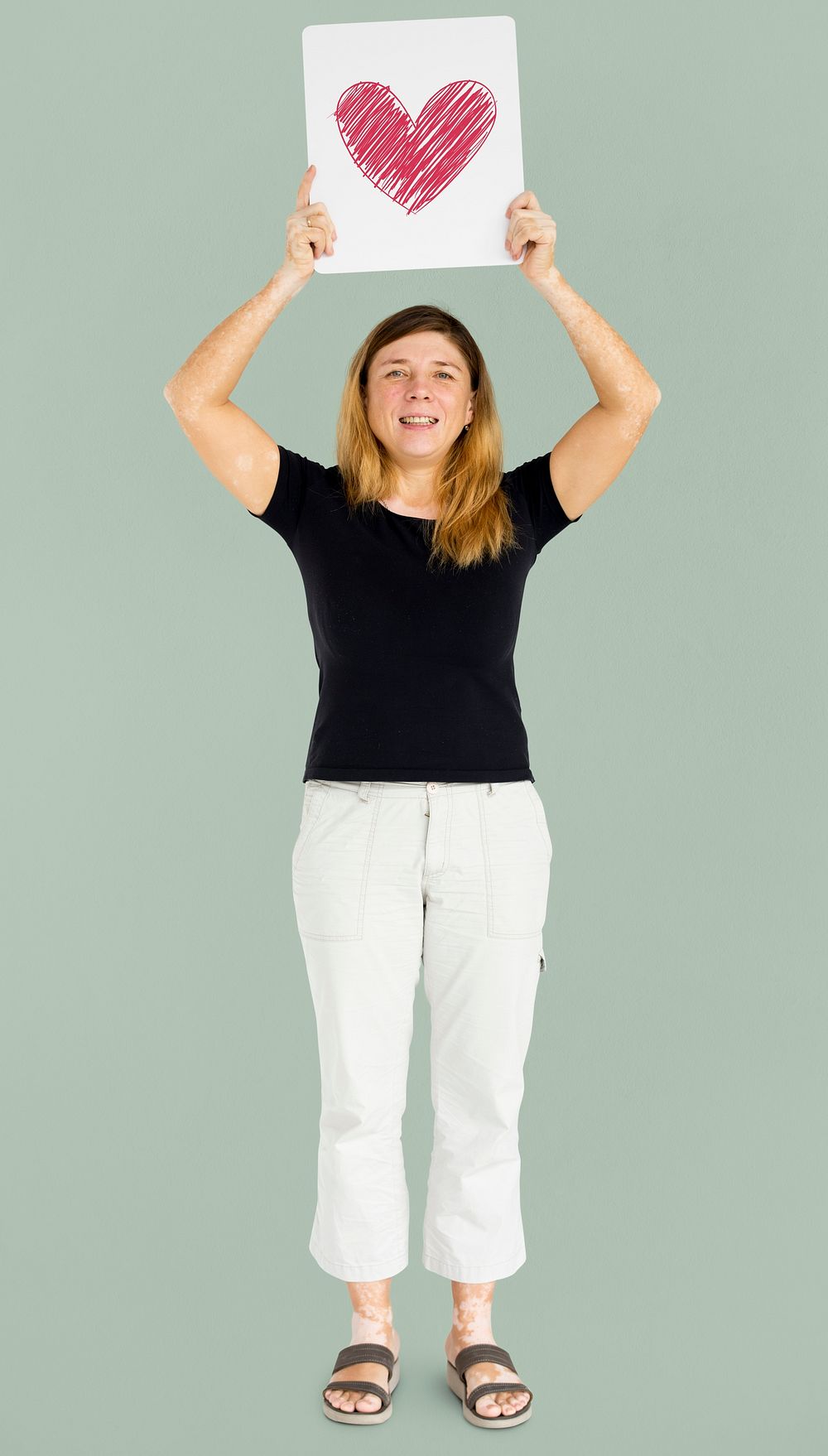 Caucasian woman full body holding board with heart sign