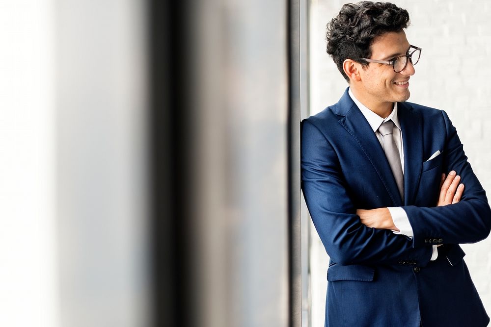 Cheerful businessman posting against the wall