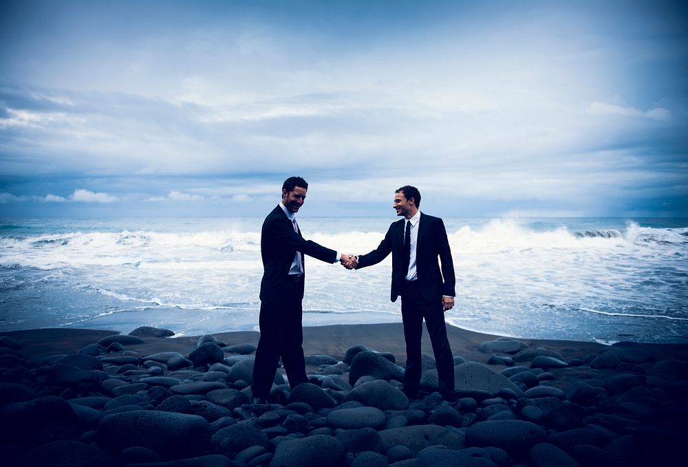 Businessmen shaking hands at a stormy ocean