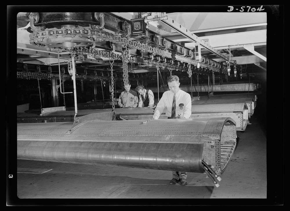 Production. Willow Run bomber plant. Checking almost-completed wing structure with blueprints, engineers at the great Willow…