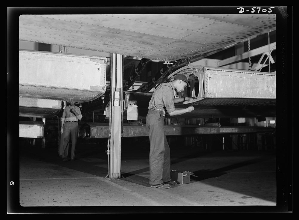 Production. Willow Run bomber plant. African American worker at Willow Run installs screws in wing segment of a bomber. Note…