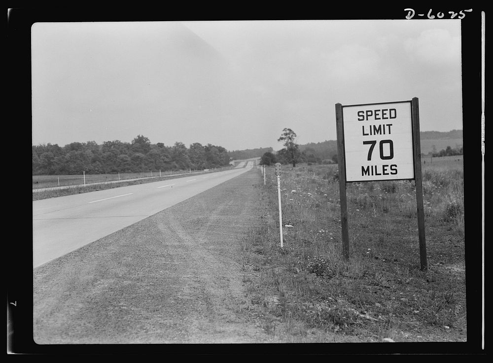 Gasoline rationing. A pre-war sign gives unnecessary warning to wartime motorists, when there are any, as weekday traffic on…
