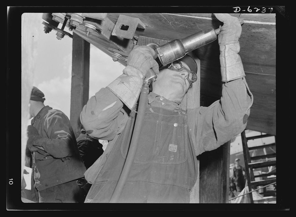 Production. Submarines. Mounting submarines on scaffoldings facilitates assembly. Here a worker rivets parts of the hull…