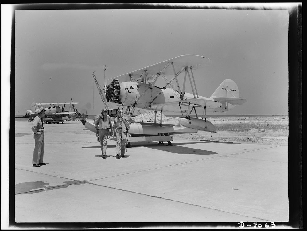Naval air base, Corpus Christi, Texas. Flight's over--an N3N training plane is safe on the dollie and pilot and instructor…