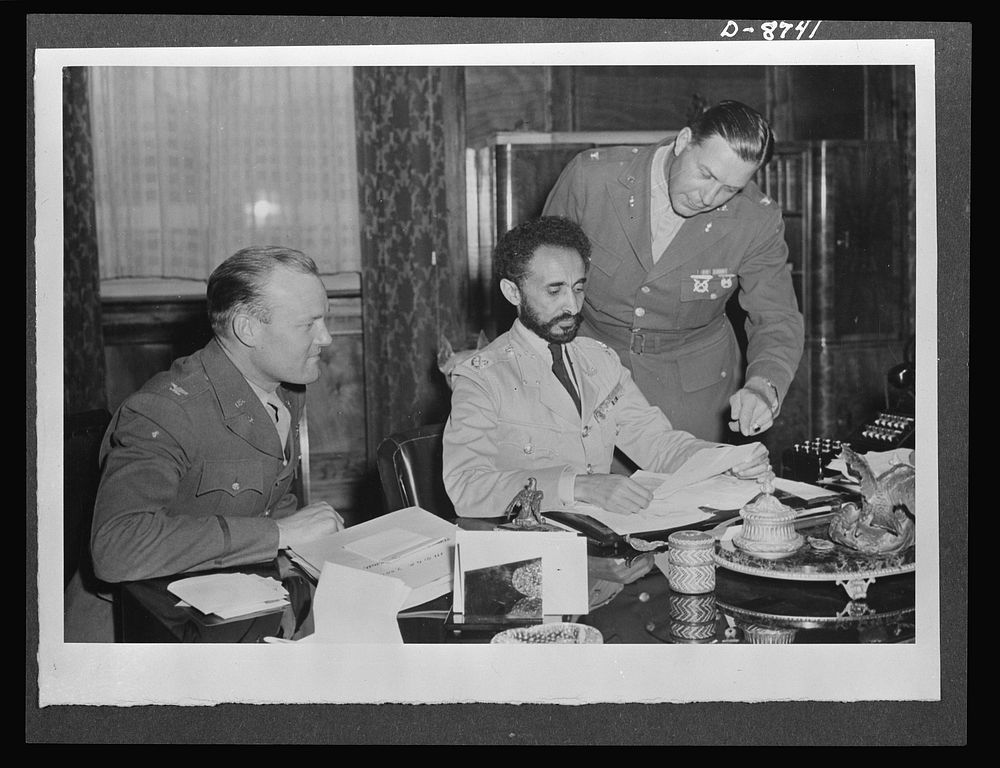 American military delegation calling on Haile Selassie. Poring over official papers. At the left of His Majesty, Haile…
