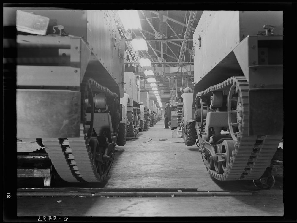 Production. Halftrac armoured cars. Partly finished halftrac scout cars travel along a moving assembly line in a plant…