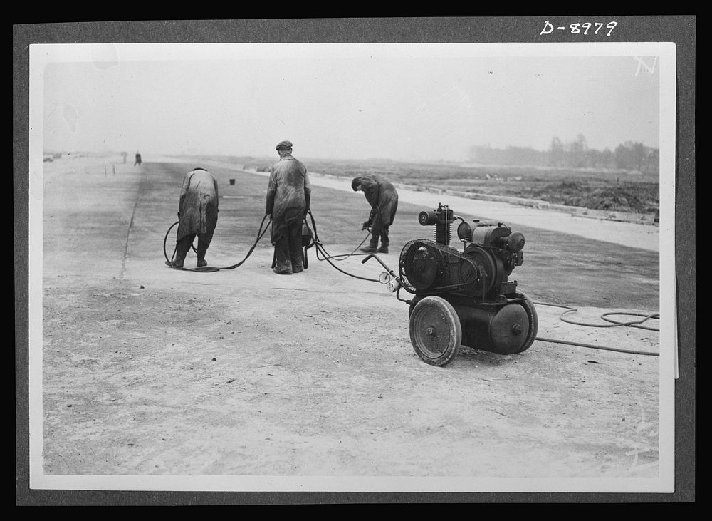 Reciprocal aid. Spraying the surface of a completed runway for an airfield in Britain for the U.S. Army Air Forces. British…