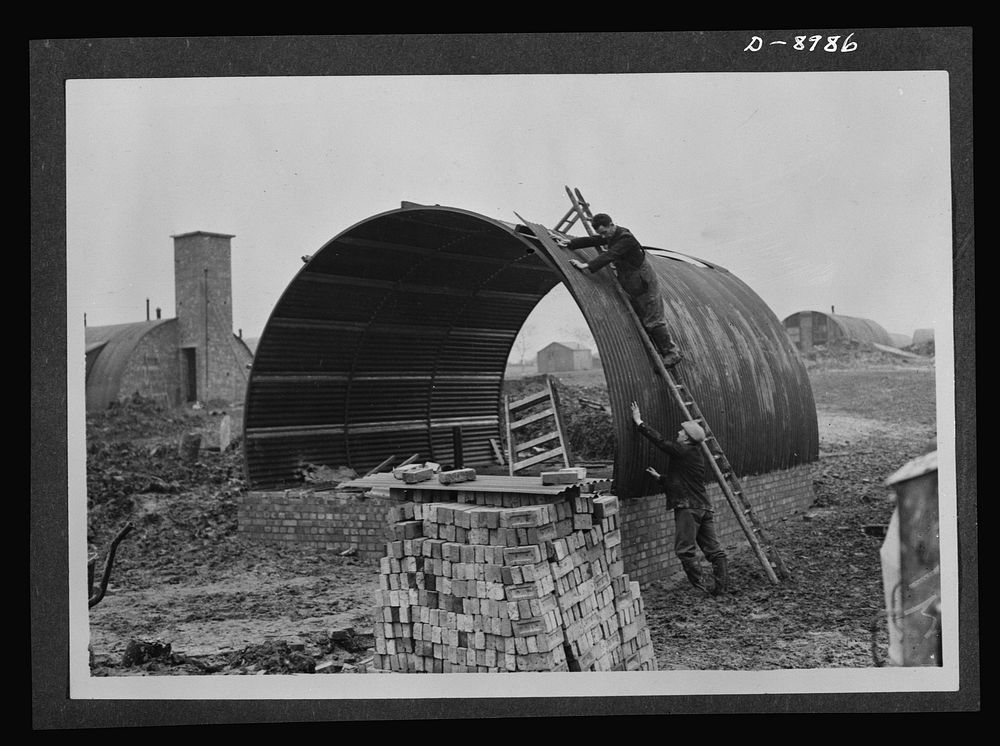 Reciprocal aid. Building a Nissen hut at an airfield in Britain for American Army Air Forces. British labor and material is…