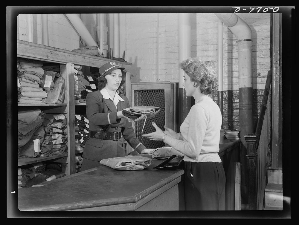 Safe clothes for women war workers. Applying for a standard uniform at the Bendix supply center, Eunice Kimball is given a…