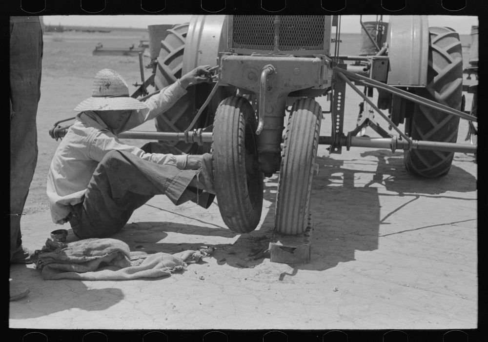 Day laborer pushing wheel onto tractor, large farm near Ralls, Texas by Russell Lee