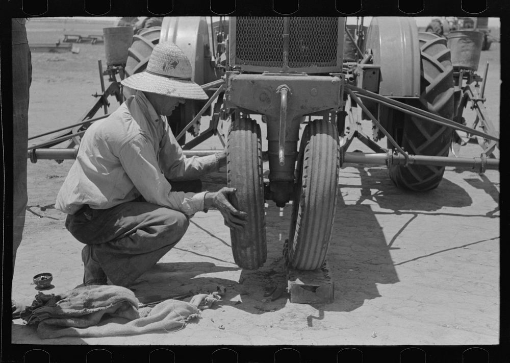 Day laborer putting front wheel onto tractor, large farm near Ralls, Texas by Russell Lee