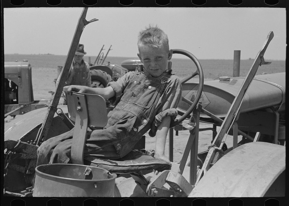 Son of day laborer sitting in tractor seat, large farm near Ralls, Texas by Russell Lee