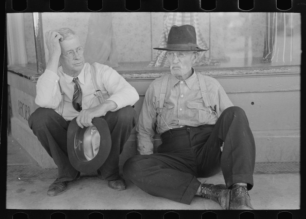 Farmers sitting against wall and squatting on sidewalk, Spur, Texas by Russell Lee