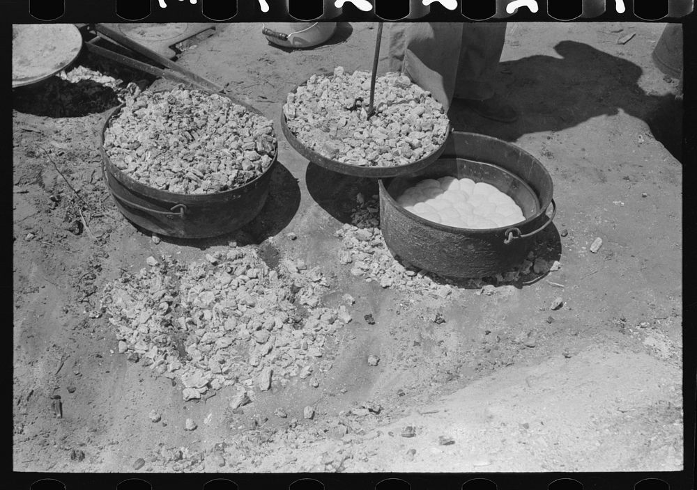 Biscuit being made in dutch oven on cattle ranch near Spur, Texas. Coals are piled on the lid of the dutch oven by Russell…
