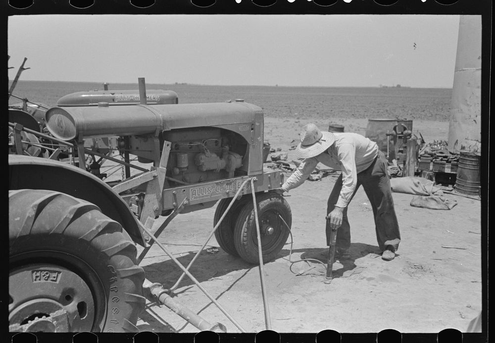 Day laborer pumping up tire on tractor on large farm near Ralls, Texas. Nine tractors were used on this farm of four…