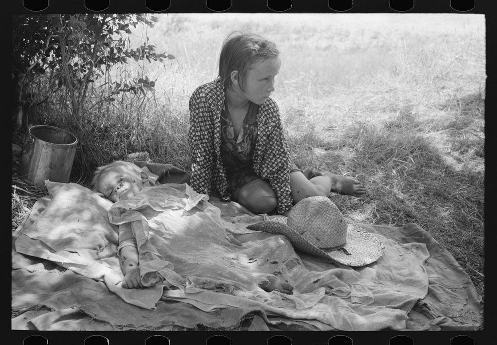 Children of agricultural day laborers camped by the roadside near Spiro, Oklahoma. There were no beds and no protection from…