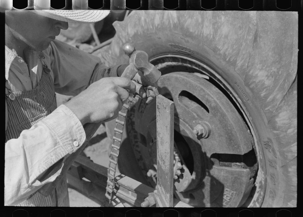 Day laborer repairing link of chain which operates planter feed, farm near Ralls, Texas by Russell Lee
