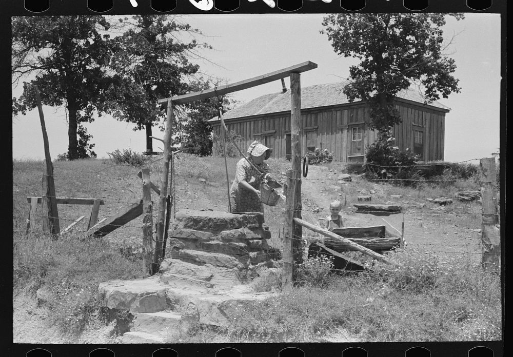 Tenant farmer drawing water at well. This woman (her husband died several months ago) and her three grown sons rent and farm…