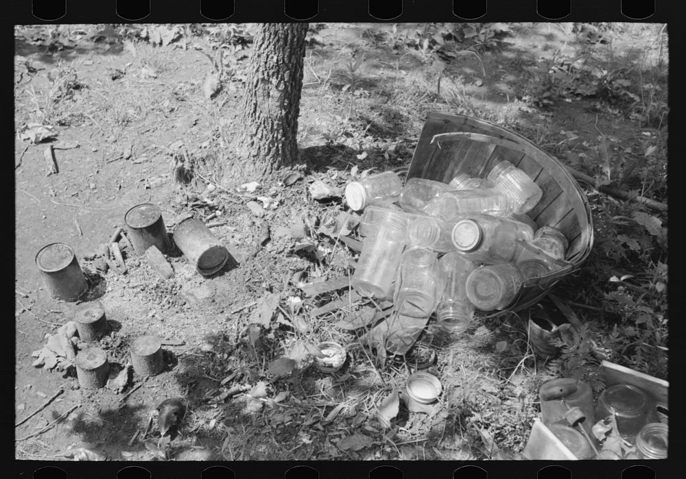 Tin cans and glass jars near camp of agricultural day laborers camped near Spiro. Sequoyah County, Oklahoma by Russell Lee