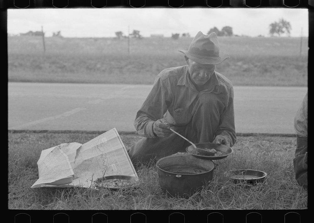 Migrant agricultural worker dishing up the noonday lunch of berry pie while camped by the roadside east of Fort Gibson…