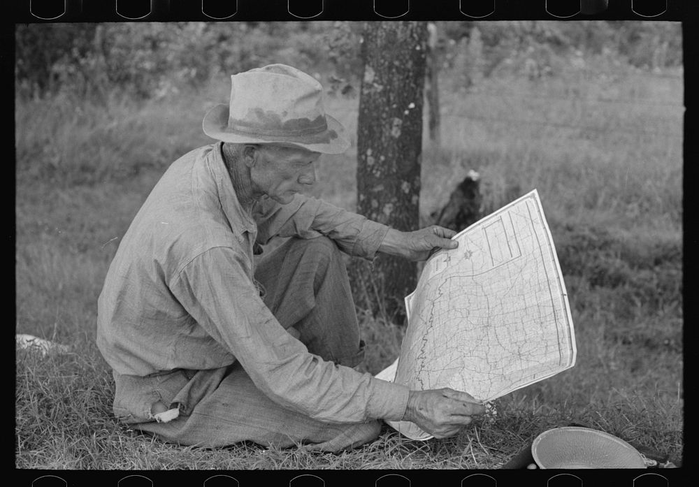 White migrant agricultural worker from Texas studying the map while stopped for lunch on the roadside east of Fort Gibson…