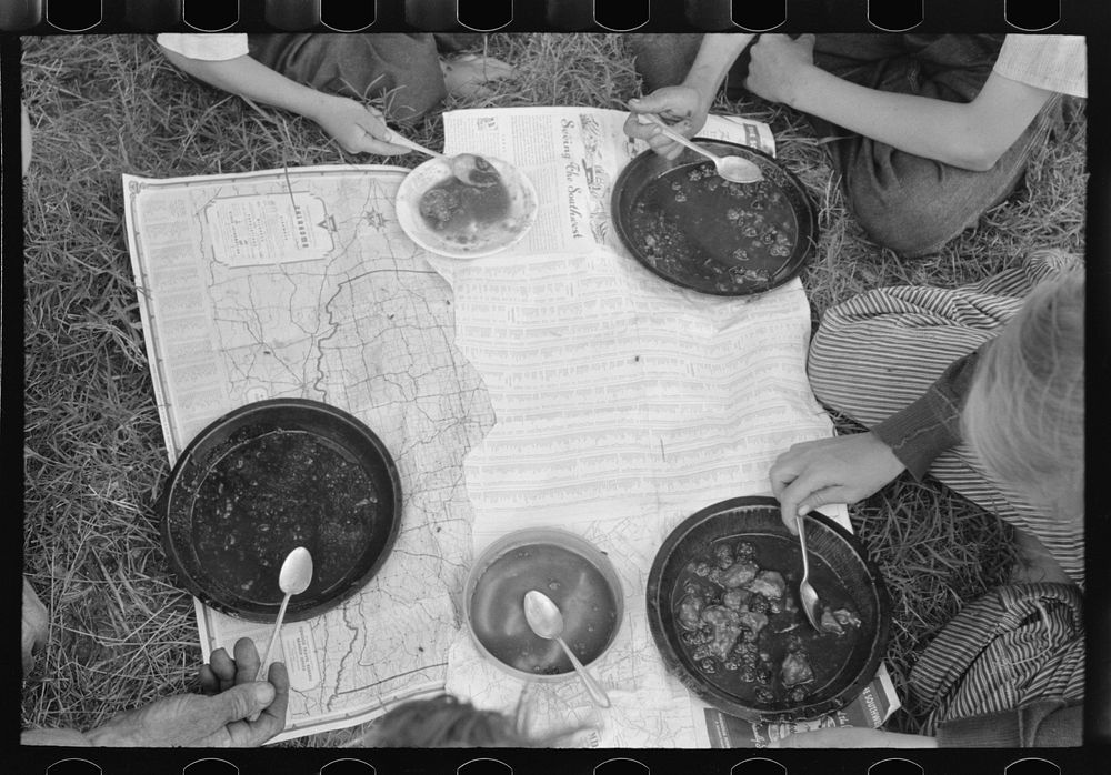 Lunch of white migrant family with map as table cloth east of Fort Gibson, Muskogee County, Oklahoma by Russell Lee