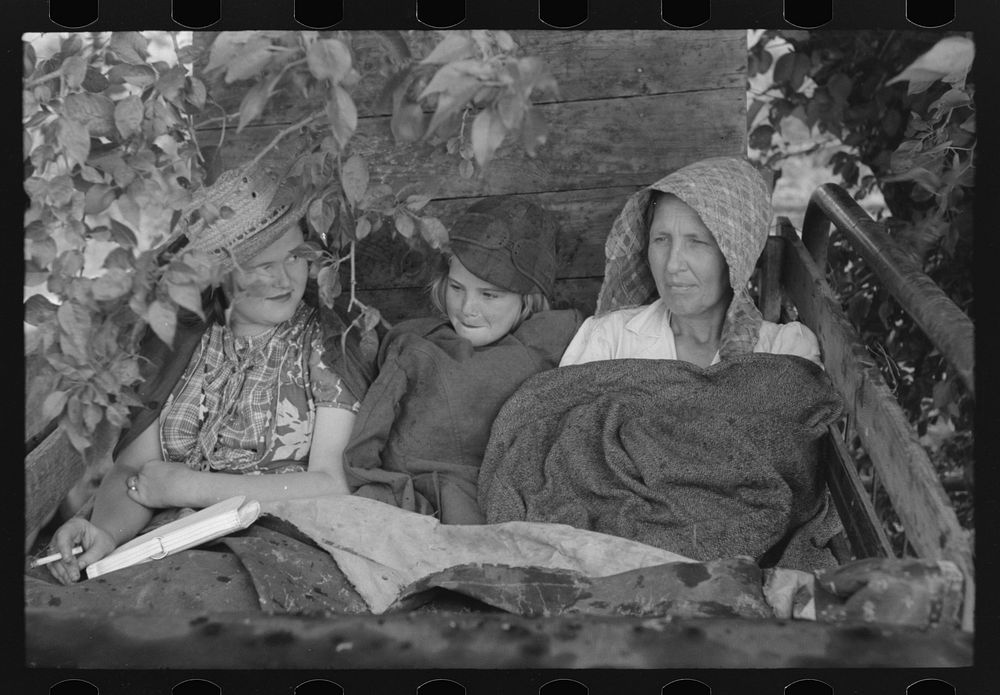 Migrant's car stopped along the road, with part of migrant family in rear seat of truck, under a tree to await the rain's…
