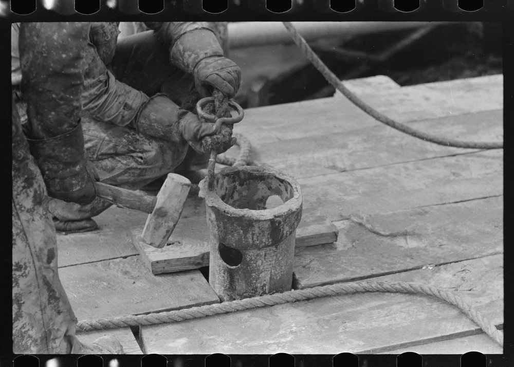 [Untitled photo, possibly related to: Roughnecks guiding bailer into hole during bailing out operations, oil well, near…