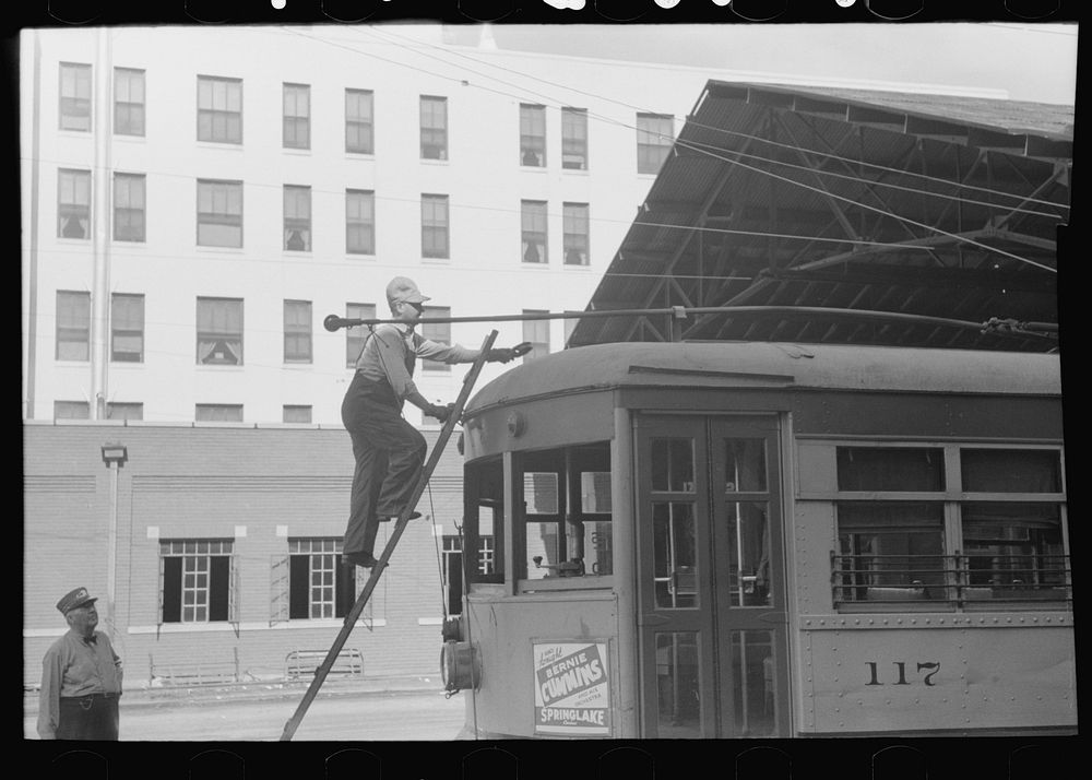Workman climbing on top of streetcar to change wheel on trolley. Streetcar terminal, Oklahoma City, Oklahoma by Russell Lee