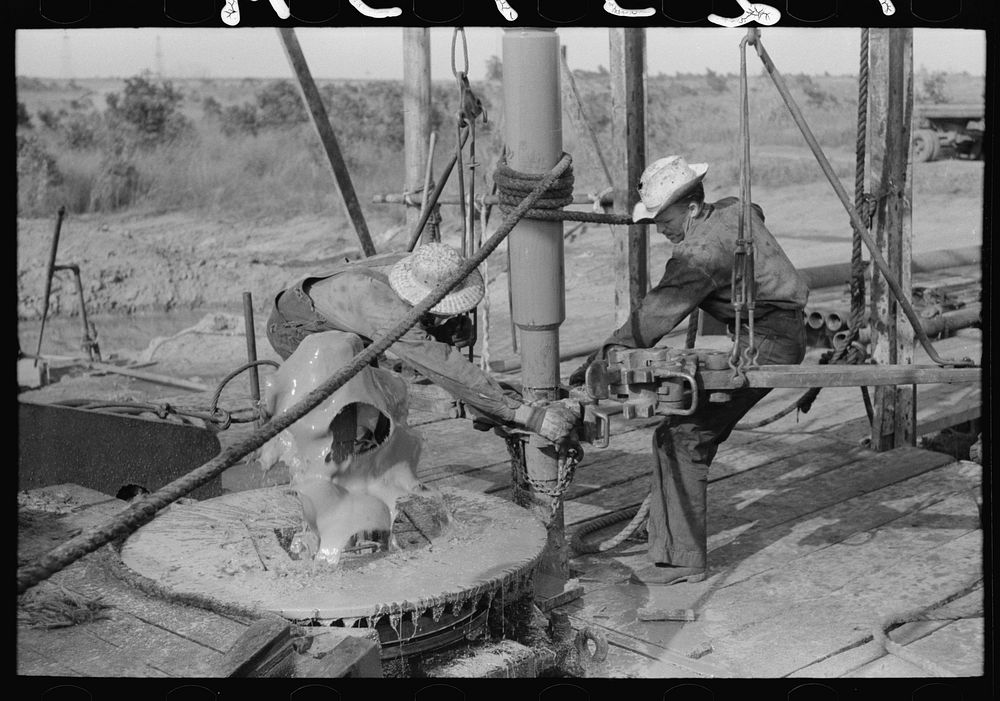 Adding a length of drilling pipe at oil well in Seminole oil field, Oklahoma. Wrench applied to loosen pipe by Russell Lee