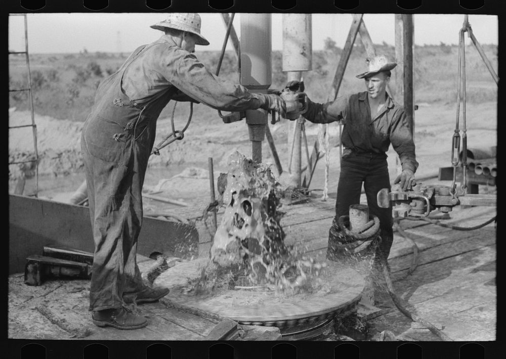 Adding a length of drilling pipe at oil well in Seminole oil field, Oklahoma. Mud spurting out as section of pipes are…
