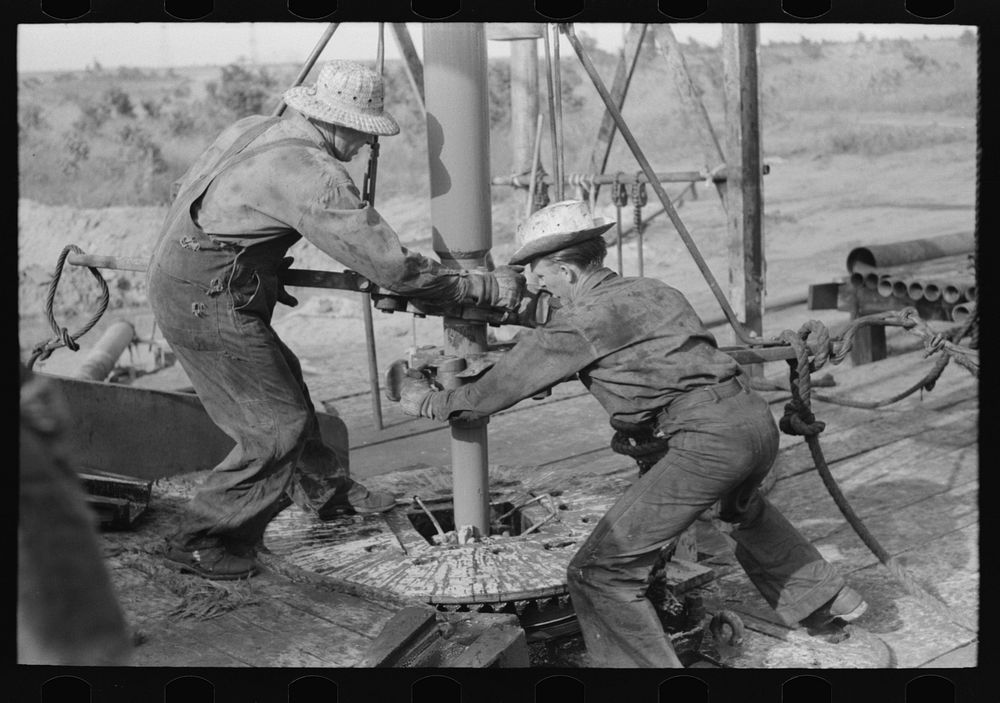 Adding a length of drilling pipe at oil well in Seminole oil field, Oklahoma. Wrenches applied to loosen pipe by Russell Lee